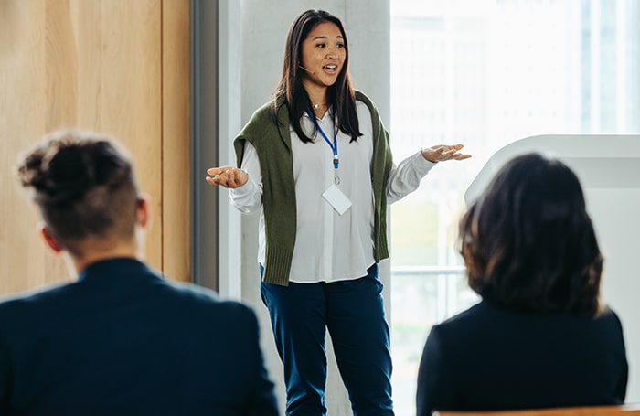 Asian woman presenting to a diverse audience 